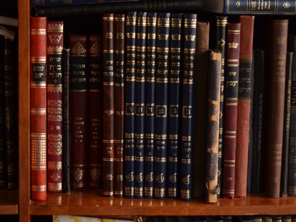 A collection of Jewish books on a wooden shelf